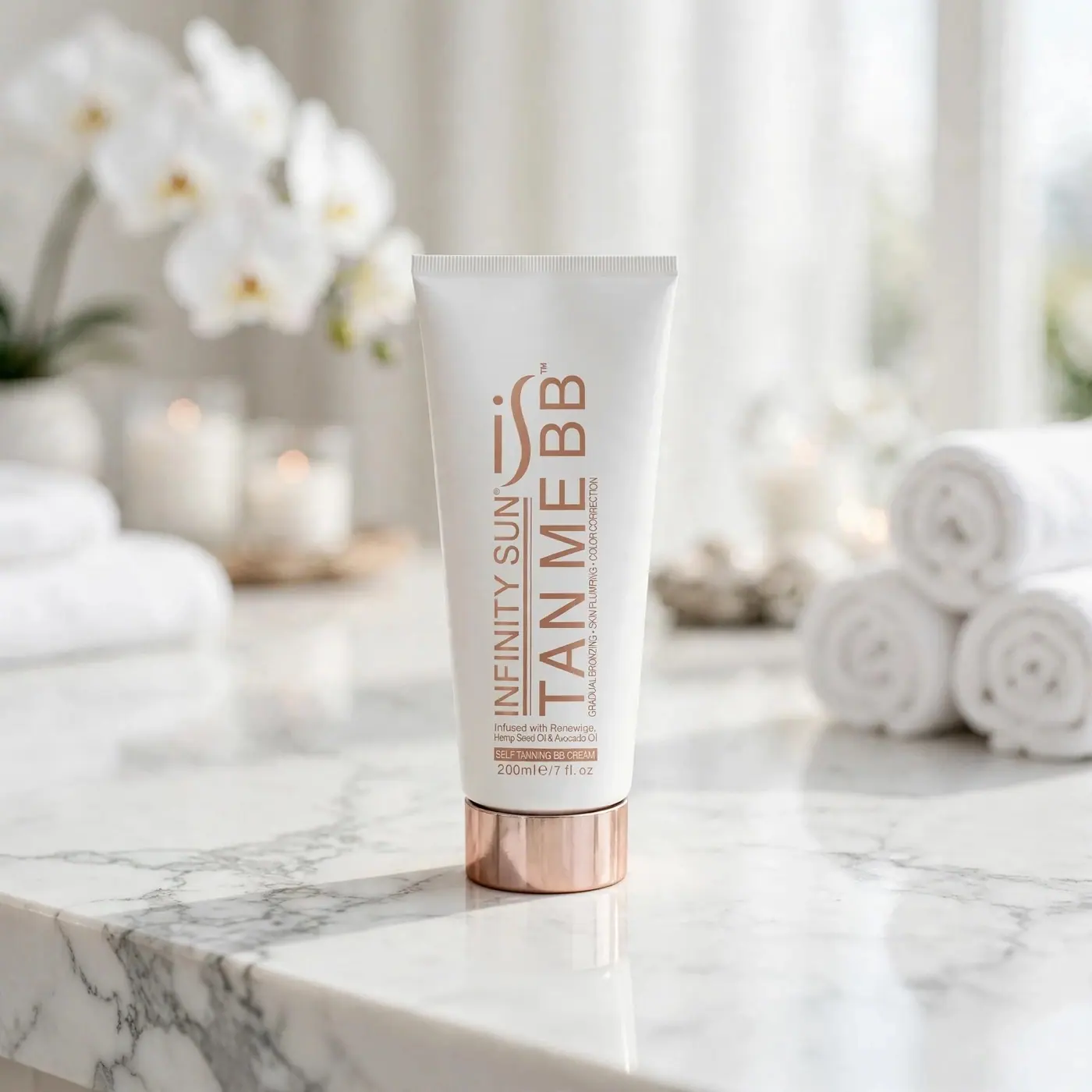 A tube of Infinity Sun Tan Me BB Cream on a marble shelf beside rolled white towels